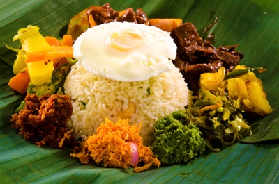 Lumprais:  rice with fried egg, roasted cashew nuts, vegetables and a deviled dish in banana leaf.